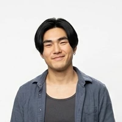 A young man in a denim shirt, photographed against a plain white backdrop.