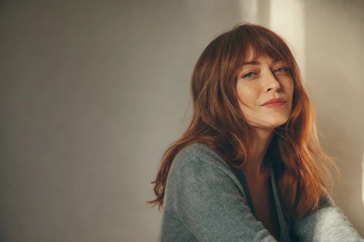 A close portrait of a red-haired woman in soft window light, made from a description.